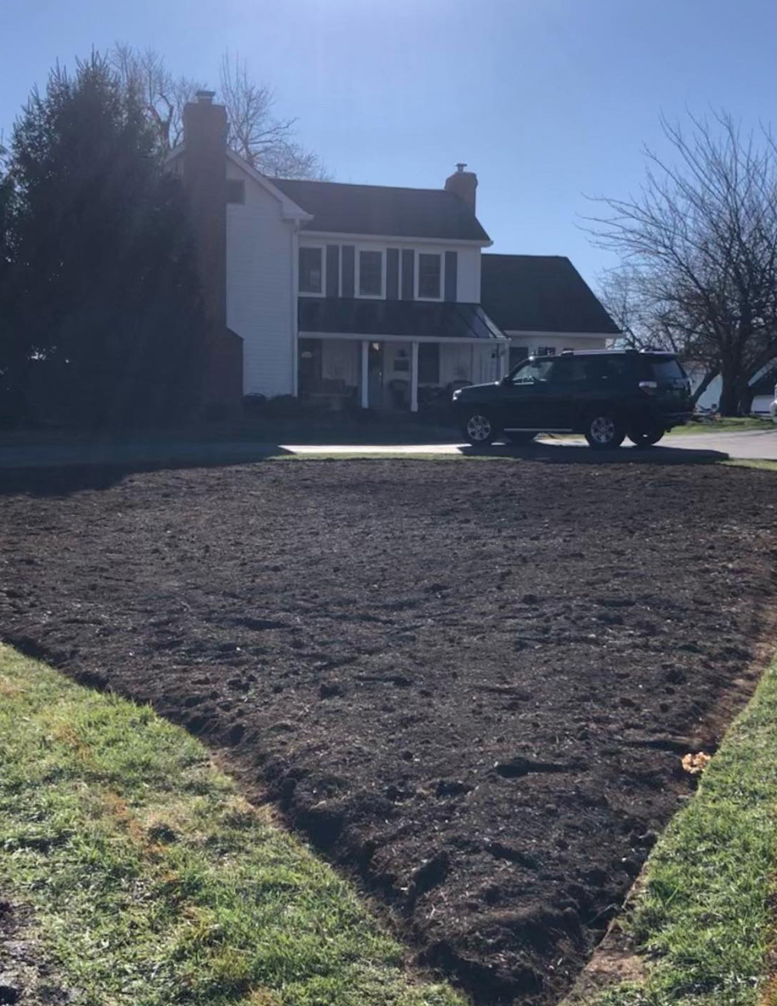 House with a driveway and freshly turned soil in front getting ready to plant a cottage garden