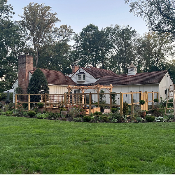Fenced in veggie garden with pergola and cottage gardens