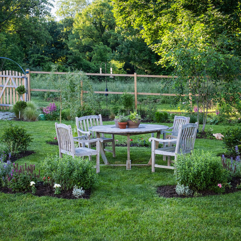 Backyard cottage garden with teak dining set and garden gate